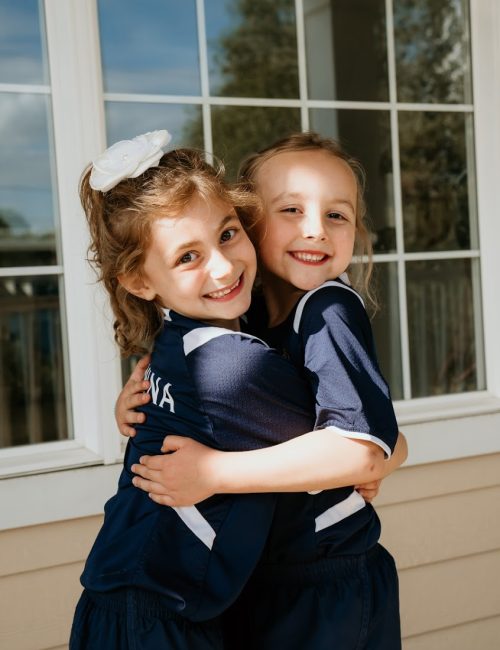 Two young students hugging and smiling in front of the Smyth School studio